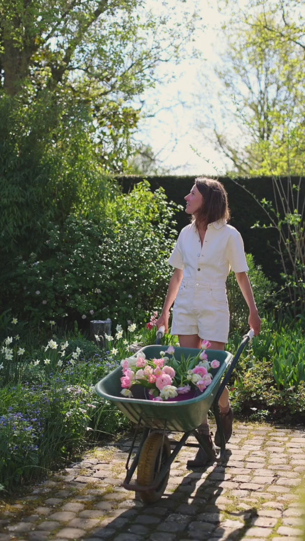Isabeau in tuin met kruiwagen vol bloemen